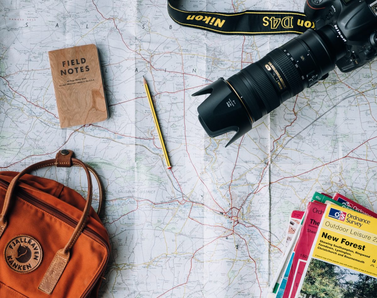 solo travel gear: camera, backpack, notebook, map